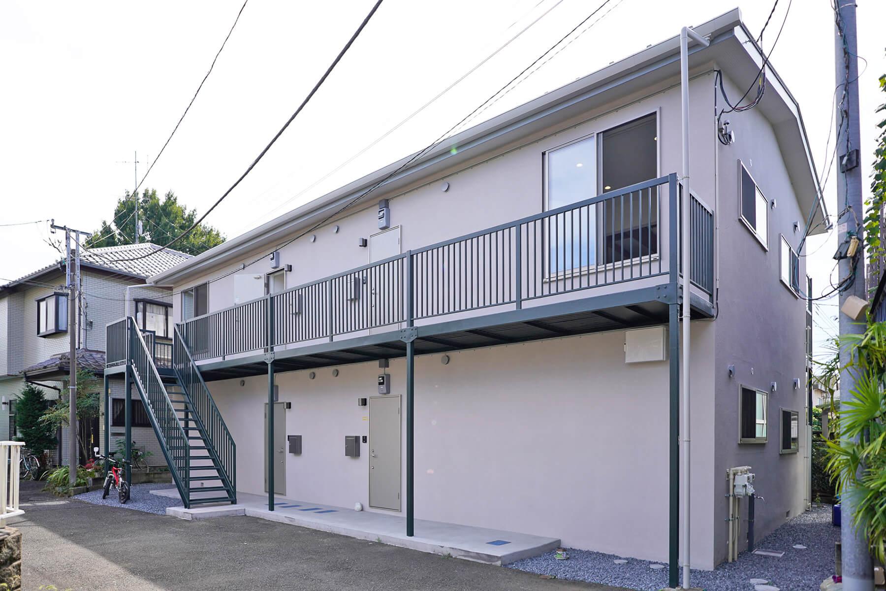 調布市富士見町の賃貸物件/外観。シンプルなグレーの外壁。外階段や手すりは深緑で、さりげないアクセントになっています