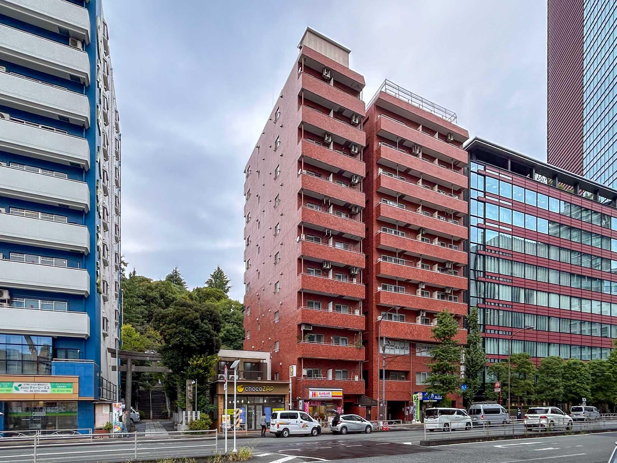 港区三田の賃貸物件/大通り沿いにふたつ並ぶ、赤い建物の左側