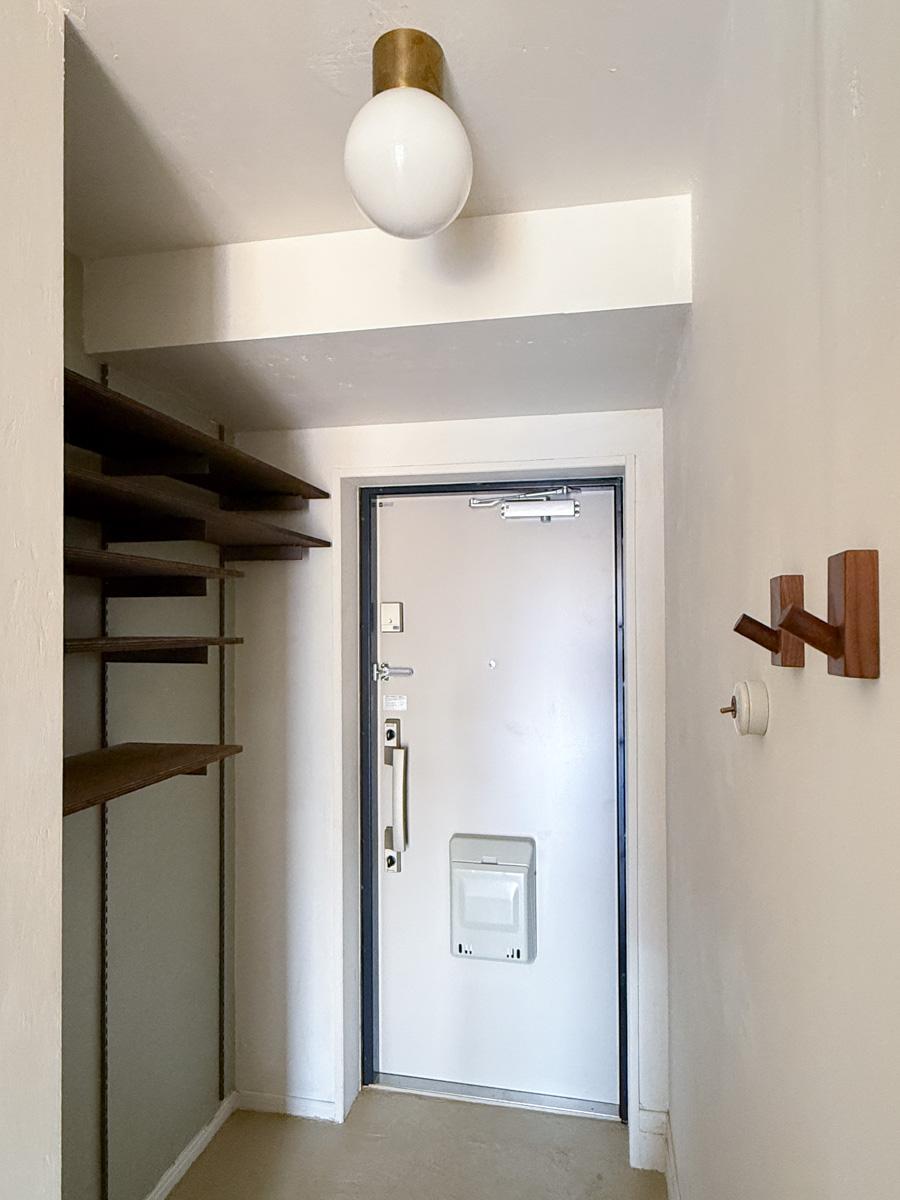 川崎市高津区蟹ケ谷の売買物件/玄関。高さの調整ができるオープンな棚が靴箱に。天井の照明は真鍮とガラスボールの組み合わせがかわいい