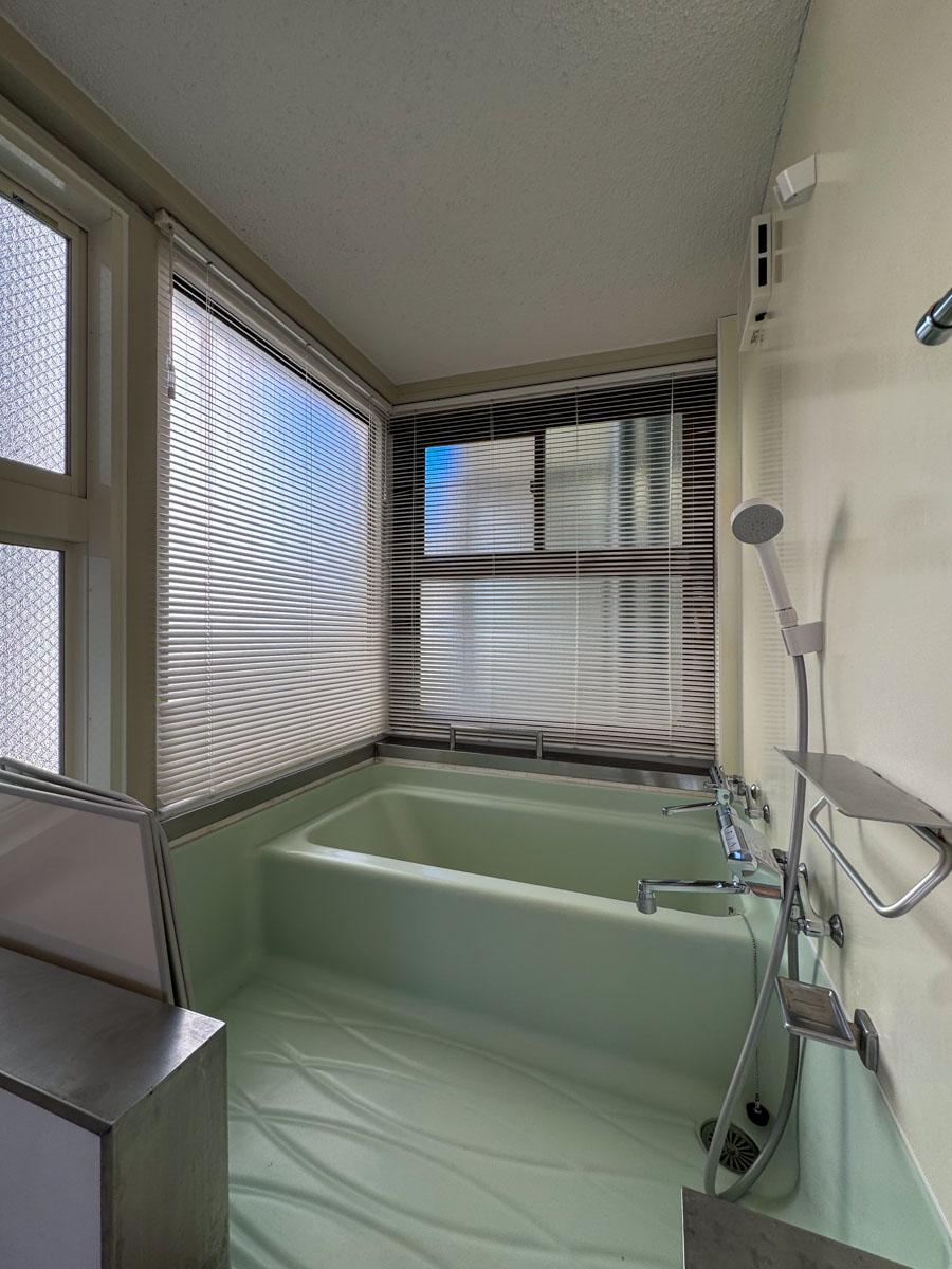 渋谷区神宮前の売買物件/浴槽は古いです。窓はすりガラスですが、透け防止のためブラインドが設置されています