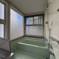 渋谷区神宮前の売買物件/浴槽は古いです。窓はすりガラスですが、透け防止のためブラインドが設置されています