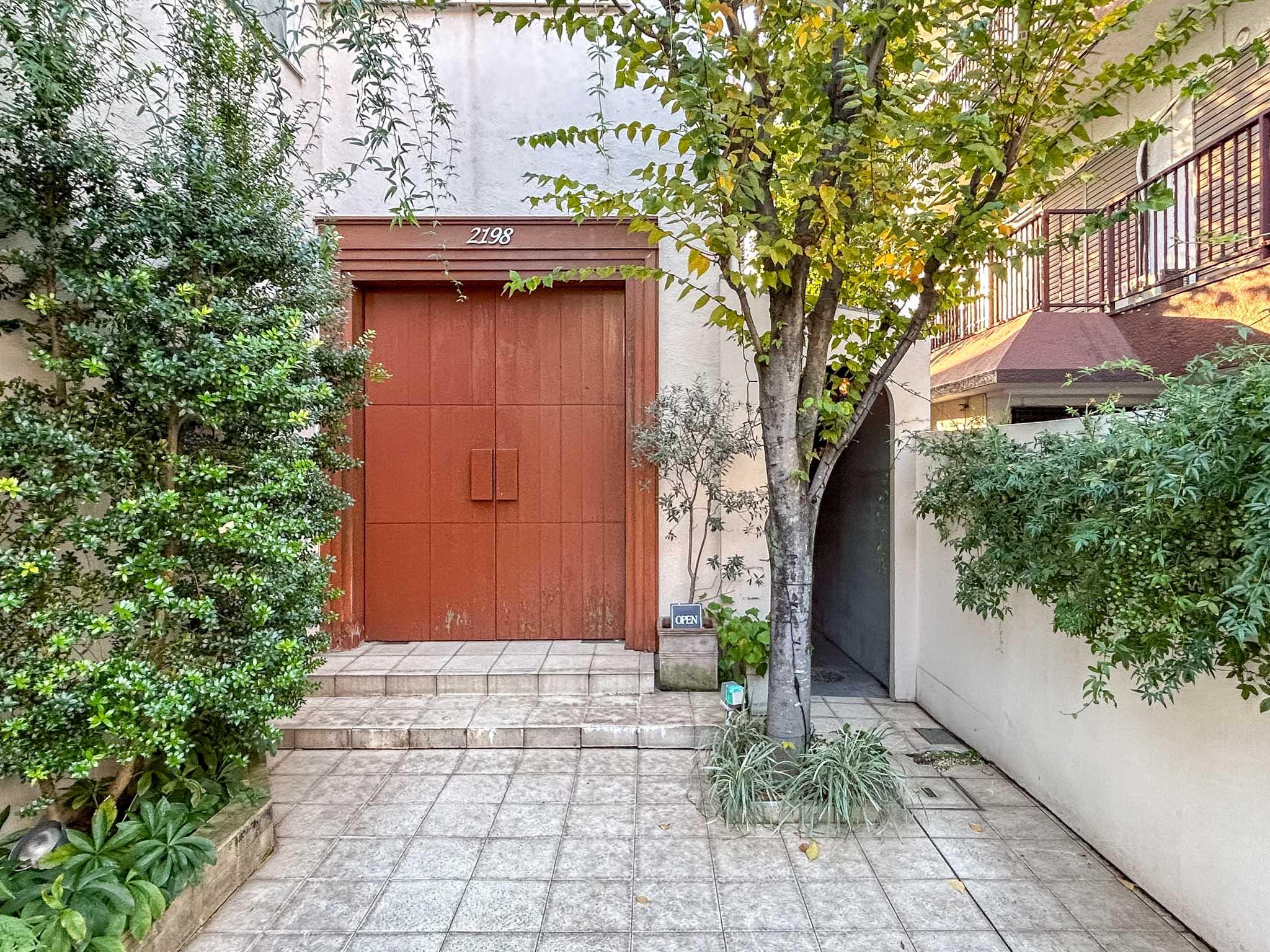 大田区山王の賃貸物件/木製の扉が印象的なエントランス。建物の1階にはちいさなカフェが併設されている