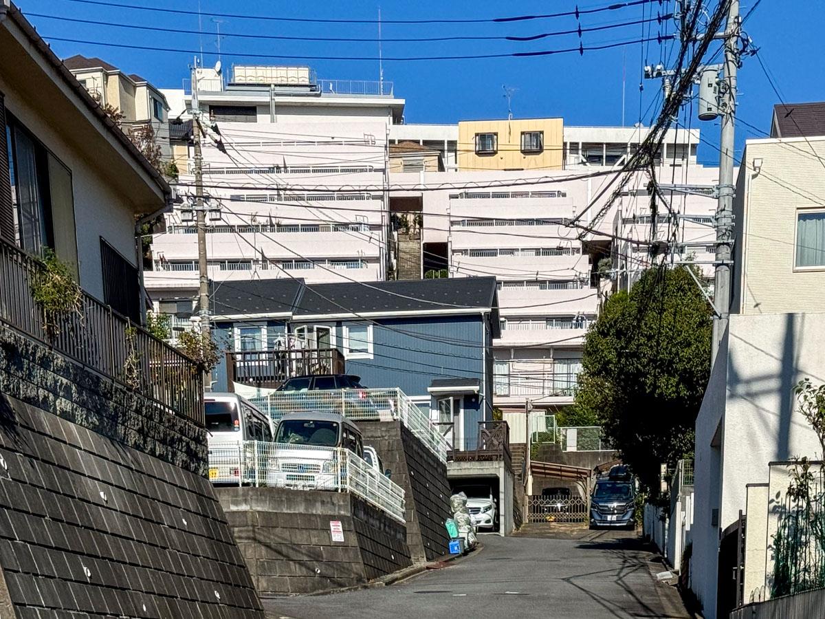 川崎市宮前区神木本町の売買物件/マンションを下から見た写真。傾斜地に階段状に立てられた、そそる姿のマンション