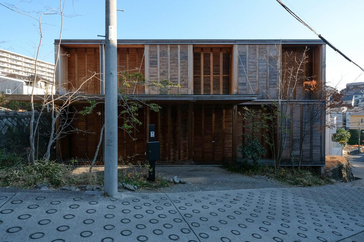 神奈川県横浜市港北区菊名の売買物件/前に倒れ込むような大きな庇とルーバーシャッターが印象的な、木の箱のような外観（正面は杉・横）。植栽も相まって素敵です