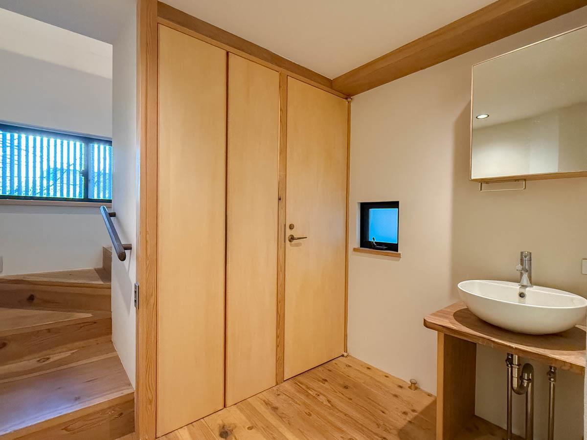 三鷹市井の頭の賃貸物件/1階に水回りがまとまっている形。木の扉の先はトイレと洗濯機置き場。脇に洗面、その右横に浴室があります