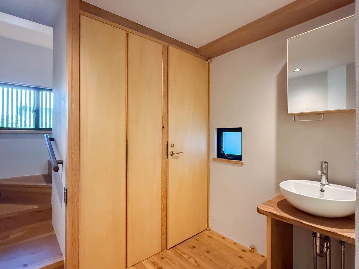 三鷹市井の頭の賃貸物件/1階に水回りがまとまっている形。木の扉の先はトイレと洗濯機置き場。脇に洗面、その右横に浴室があります