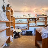 八王子市七国の売買物件/こちらはアトリエゾーンの入口。木製の棚が壁沿いに並び、作品がたくさん展示されています
