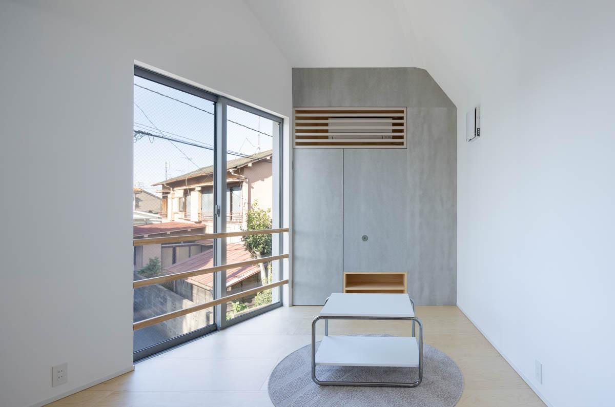 東京都昭島市東町の売買物件/リビング。モルタルのようなグレーの質感をもつフレキシブルボードがアクセント。その裏には人が入れるくらいの広さのある収納スペースがつくられています