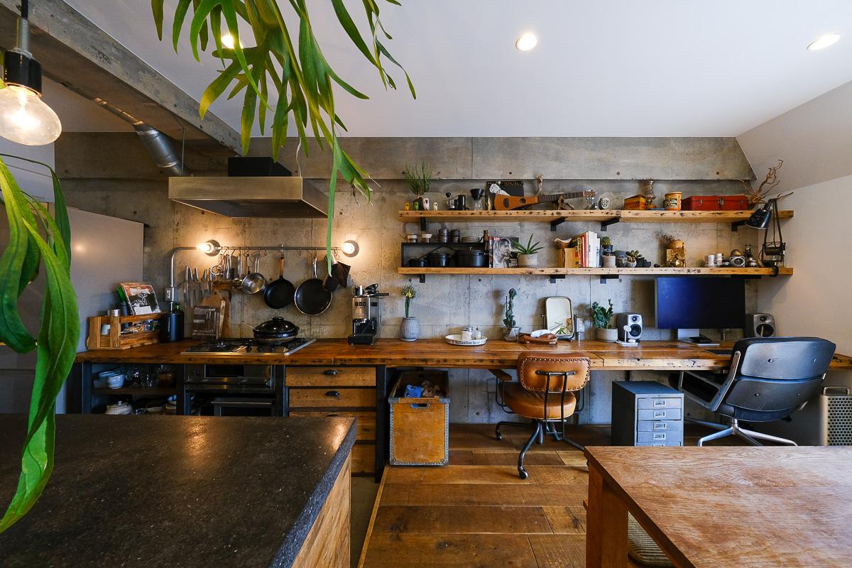 世田谷区玉堤の売買物件/ほとんどの壁面を白く塗装した中、あえてキッチン側の壁面は無塗装。キッチンから続く古材のカウンターは作業デスクとして利用中