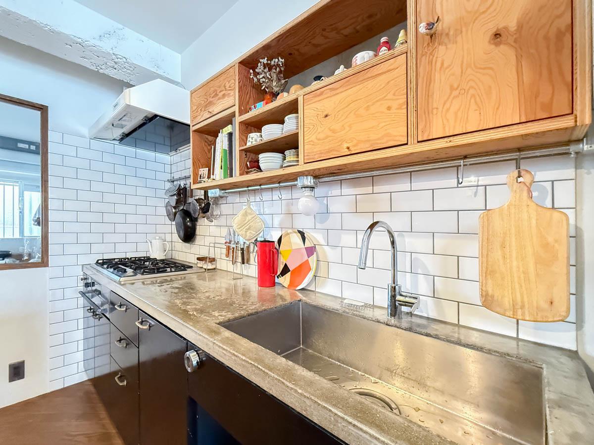 横浜市港北区富士塚の売買物件/モルタルでつくられた挑戦的なキッチン。木製の造作収納や白いタイルがマッチします