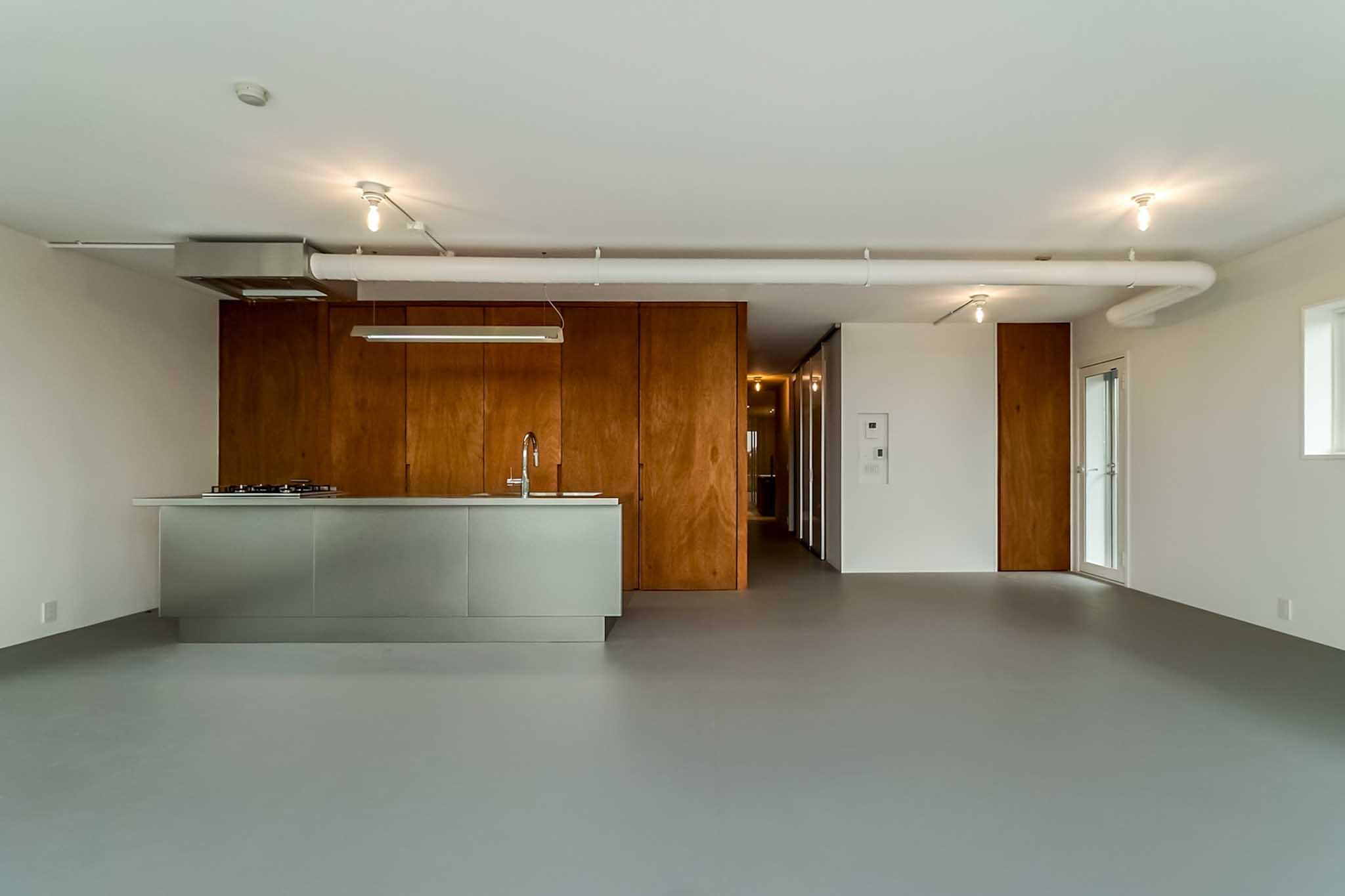 横浜市港北区師岡町の売買物件/キッチンの方をみる。木質の建具が無機質な空間によく馴染んでいます