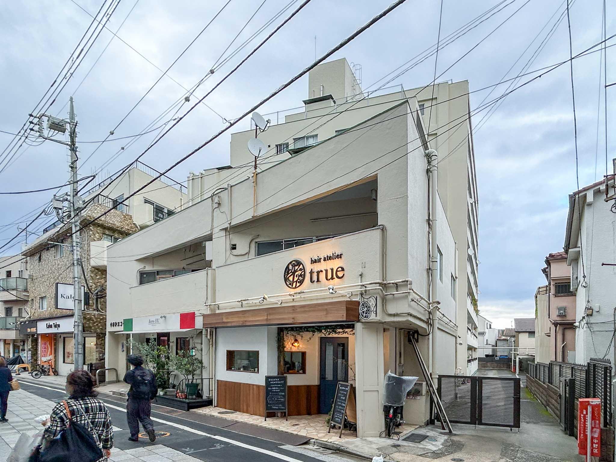 中野区新井の賃貸物件/外観。1階にイタリアンと美容室が入っています。向かって右手の通路の先に駐輪場があります