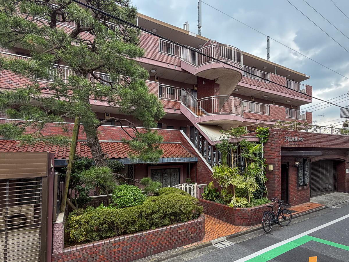 中野区本町の賃貸物件/赤茶のタイル張りの外観。立派な松の出立ちが、この建物の歴史を象徴しています。