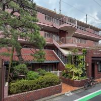 中野区本町の賃貸物件/赤茶のタイル張りの外観。立派な松の出立ちが、この建物の歴史を象徴しています。