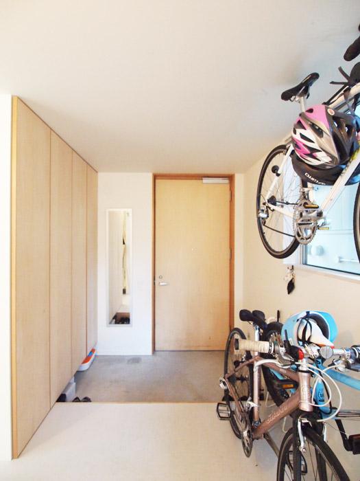 玄関は自転車やベビーカーなどが置ける。シナの素材が優しい。