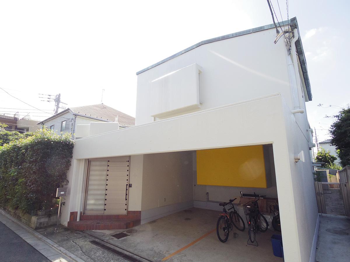 まっ白な外壁の外観。駐車場奥の黄色い壁部分はキッチンの収納部分が飛び出ている