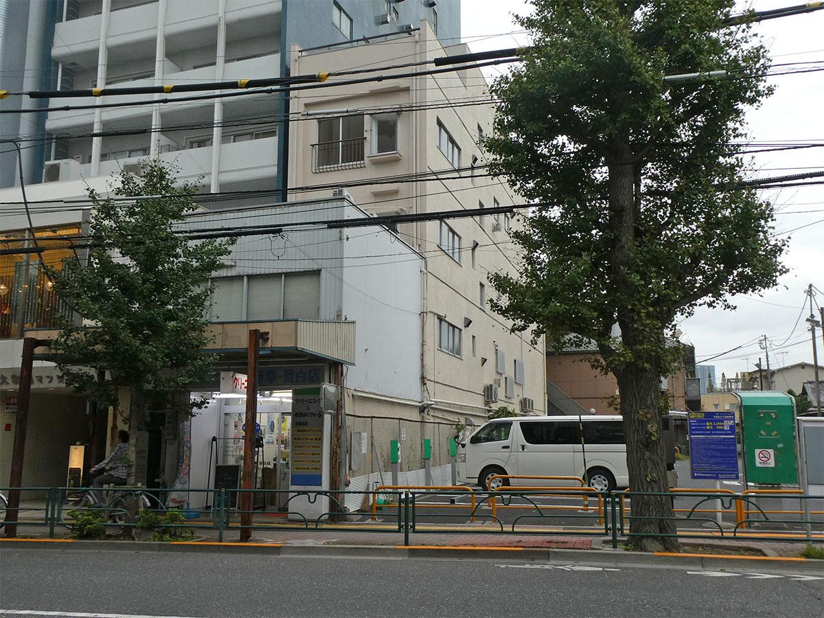 外観。奥まっているクリーム色のビルの4階。隣は駐車場