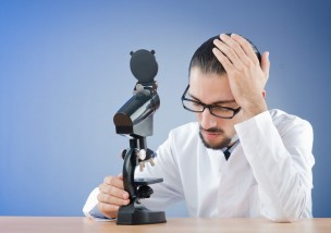 悩む白衣の男性と顕微鏡