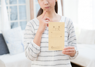 給与の封筒を持って悩む女性
