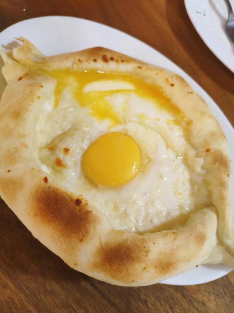 我が名はアルトゥル‼️日本の皆様おはようございむわぁす‼️これは日本の目玉焼きに似てるだけど、全然違うジョージア料理“アジャルリハチャプリ”‼️船の形したパンの中にとろとろチーズとバター、卵黄が入ったカロリーのモノノケ‼️見た目と名前のかわいさから油断して朝から食べたら動けなくなるぞ‼️