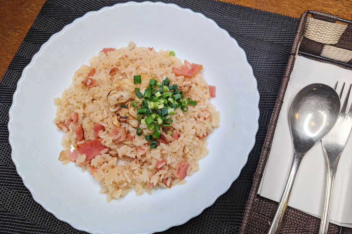 【絶品すぎるガーリックライス】 ①フライパンにバターを入れ弱火でベーコン、にんにくを炒め、にんにくに焼き色がついたらごま油を入れる ②ベーコンに火が通ったらごはん、めんつゆ、鶏ガラの素、ブラックペッパーを混ぜ、皿に移してネギをのせて完成