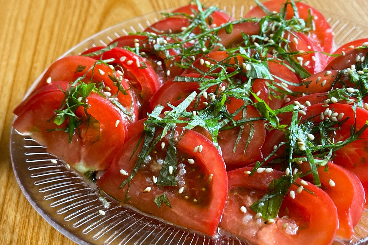 やみつき無限トマト  ①トマト3個を薄く半月型にスライス ②大葉1枚を細かく刻む ③鶏がらとにんにく各小さじ1を水小さじ1に溶かし、ごま油大さじ2とよく混ぜて特製ダレを作る ④お皿にトマトを盛り付け特製ダレをかけたら大葉と白ごまをふりかけて完成