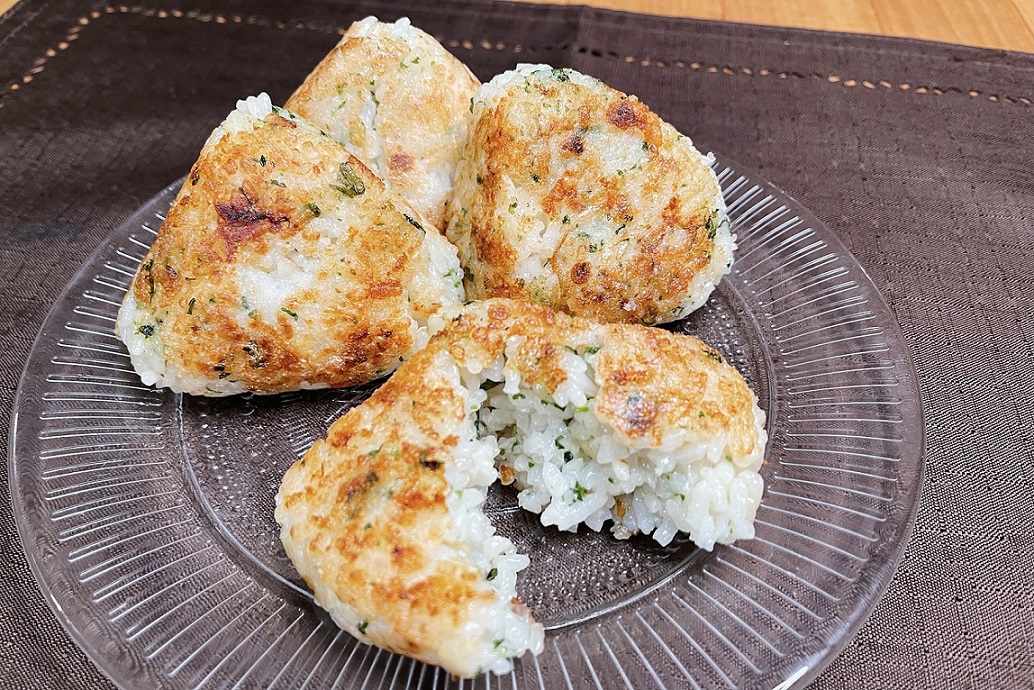 悪魔のチーズ焼きおにぎり】 ①大葉を細かく刻む(手でちぎってもOK) ②白ご飯に天かす、大葉、めんつゆ、青のり、チーズを混ぜ込んだらおにぎりの形にする ③フライパンにごま油をひいて表面をカリっと焼き上げたら完成