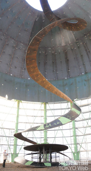 クレーン車のゴンドラに乗った作業員が、ガス切断器でてっぺんから1.5m幅でらせん状に切れ目を入れていき、鉄板そのものの重さで地上に安全に落としていきます 