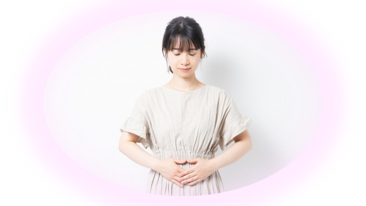 女性がお腹に手を当て、ゆっくり呼吸を整えている様子。呼吸と緊張がゆるみ、体内のめぐりが整っていくイメージを表す写真。