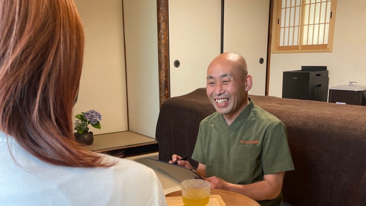 宝塚のそらまめ整体院の院長が、患者様からの不調のご相談を受けて笑顔でカウンセリングを行なっている一場面