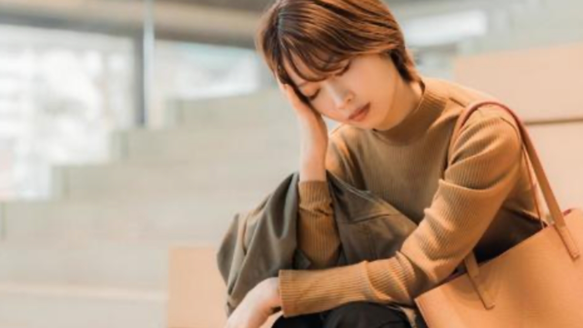 寒暖差疲労に悩み座り込む、出勤途中の女性のイメージ画像