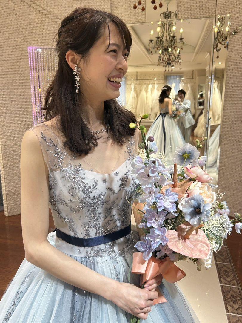 淡いブルーのウェディングドレスのデコルテ付近を確認している写真。顔まわり、アクセサリー、胸元の装飾がわかる