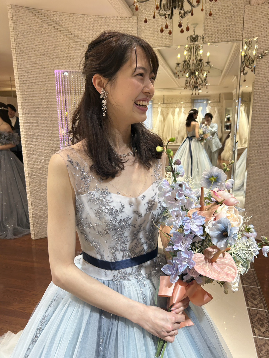 淡いブルーのウェディングドレスのデコルテ付近を確認している写真。顔まわり、アクセサリー、胸元の装飾がわかる