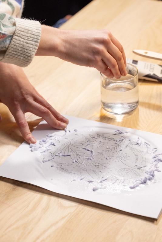 3.表面を軽く水で湿らせ、乾いた布でやさしく擦って紙の層を取り除きます。デザイン転写後、彫刻刀で彫った部分の残りのデザインも霧吹きで湿らせるときれいに取り除けます。