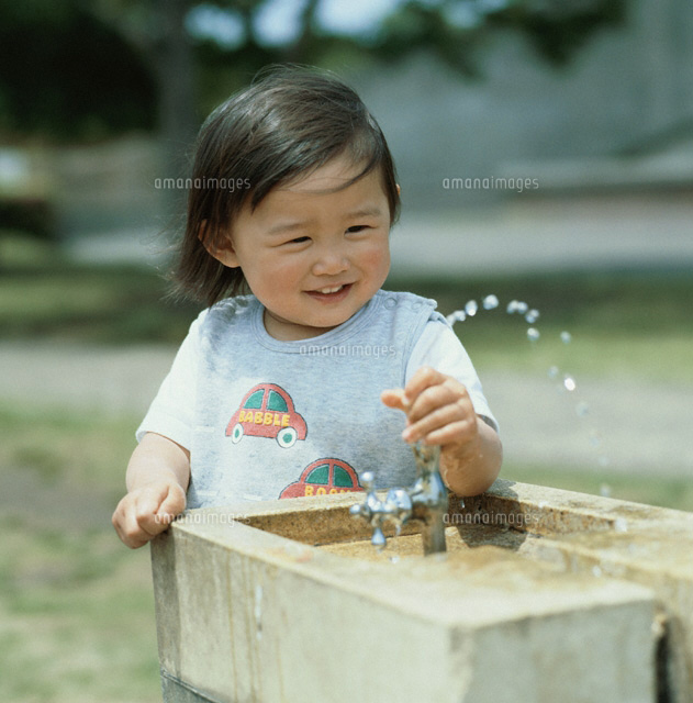 春に水道で水遊びをする日本人の女の子 5月 01315000882 の写真素材