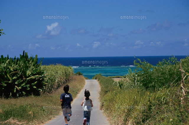 海へ続く道を走る男の子と女の子の後ろ姿 の写真素材 イラスト素材 アマナイメージズ