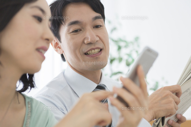 スマートフォンを見る夫婦 の写真素材 イラスト素材 アマナイメージズ