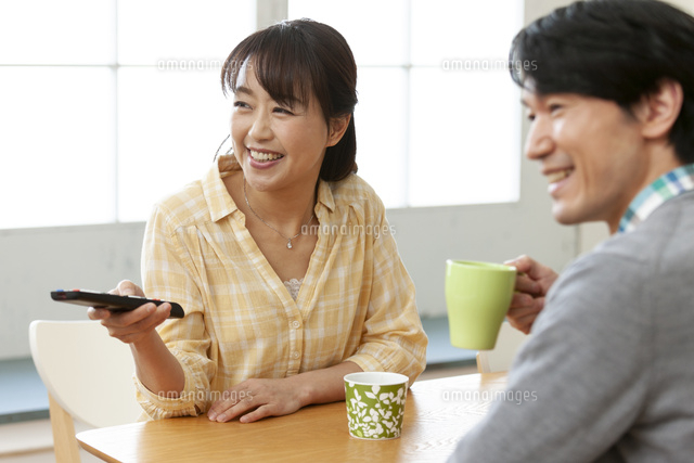 ダイニングでテレビを見る夫婦 の写真素材 イラスト素材 アマナイメージズ