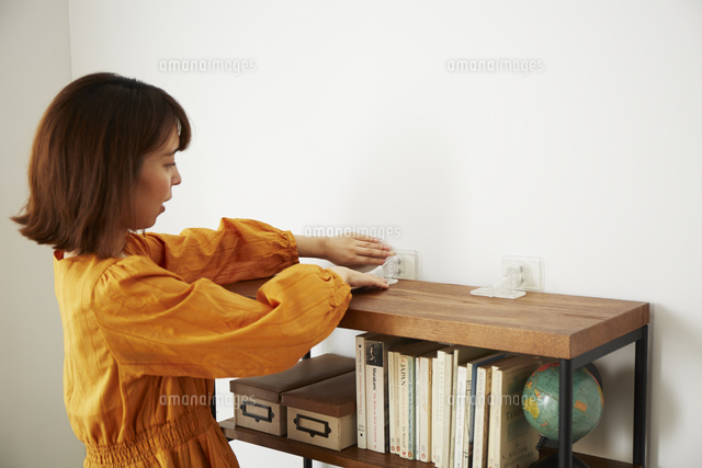 本棚に転倒防止グッズをつけている女性
(c)IDC/a.collectionRF