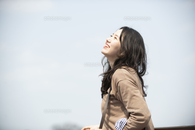 空を見上げて笑っている女性 の写真素材 イラスト素材 アマナイメージズ