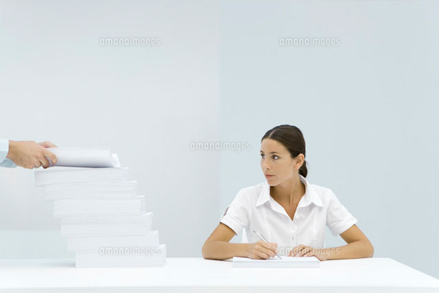 Woman sitting at table, looking at staggered stack of paper
(c)Alix Minde/PhotoAlto