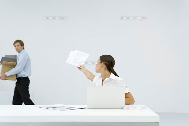 Woman sitting at desk, reaching back to hand documents
(c)Alix Minde/PhotoAlto