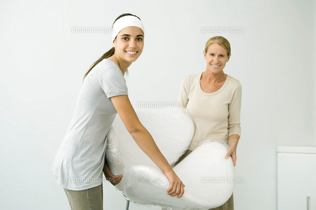 Mother and daughter carrying chair covered in bubble wrap
(c)Alix Minde/PhotoAlto