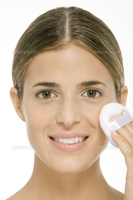 Woman using powder puff on cheek,smiling at camera
(c)Alix Minde/PhotoAlto