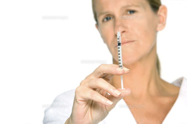 Woman holding up syringe,looking at camera
(c)Alix Minde/PhotoAlto