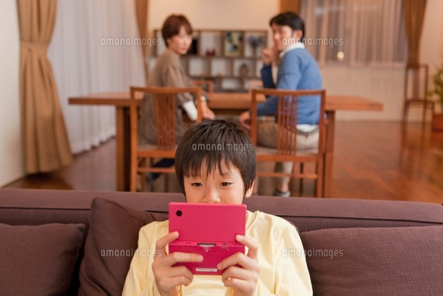 ゲームに熱中する男子中学生と眺める両親 の写真素材 イラスト素材 アマナイメージズ
