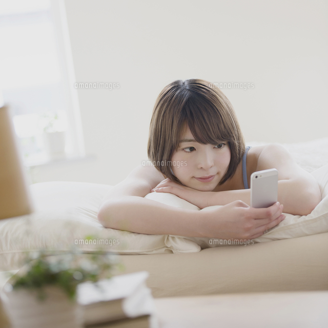 ベッドでスマートフォンを見る女性
(c)visual supple