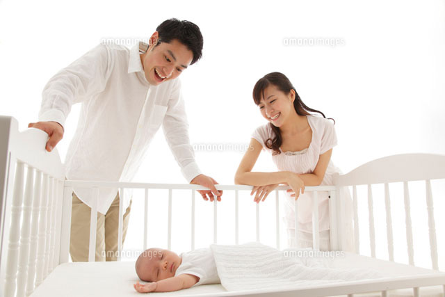 ベビーベッドで眠る新生児を見守るパパとママ
(c)mon printemps