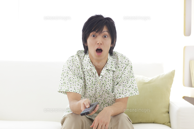 ソファーに座りリモコンを手に驚いた顔の男性
(c)mon printemps