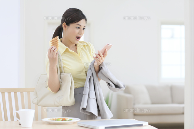 出勤前にスマートフォンを見ながら朝食を食べる女性
(c)mon printemps